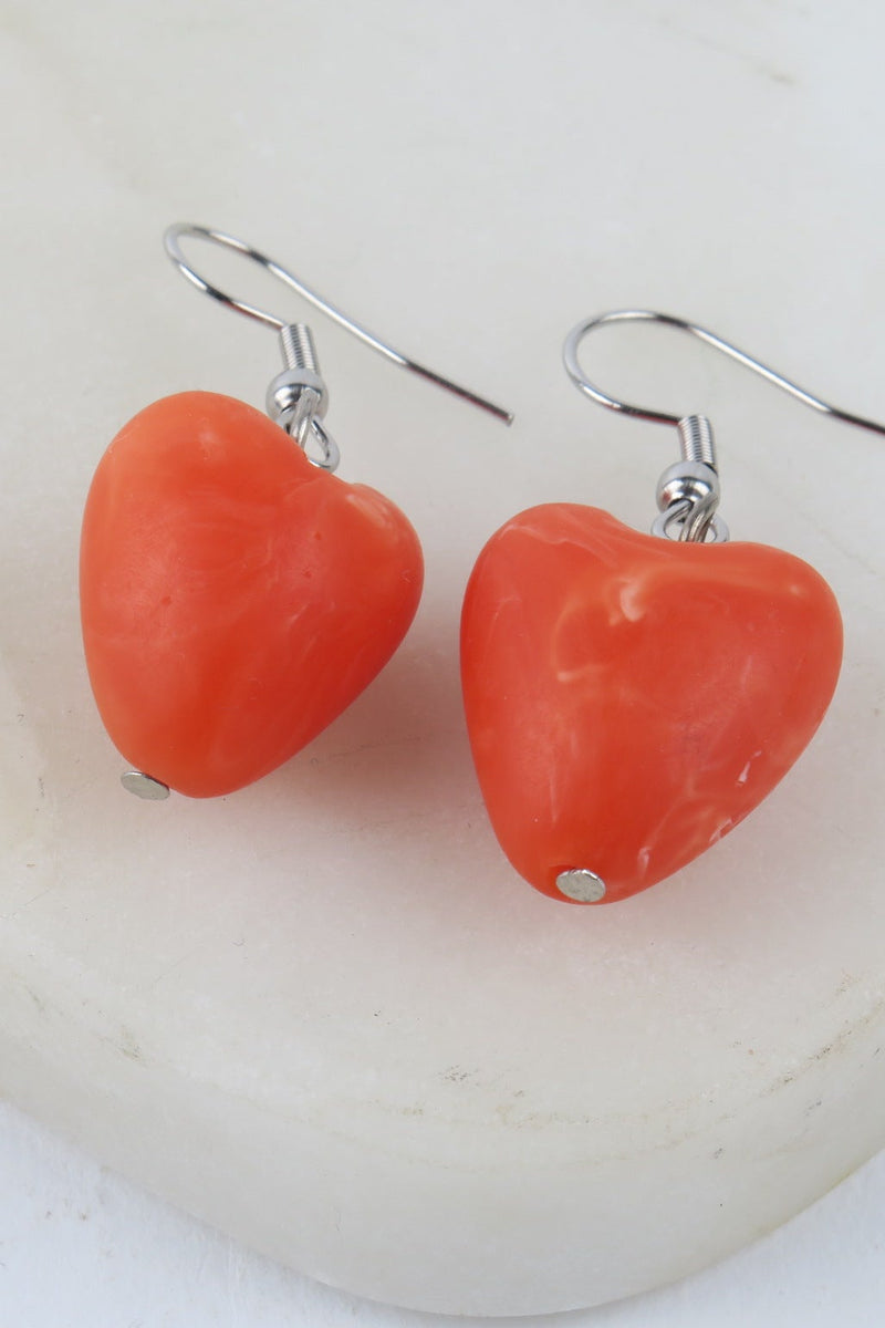 Heart-shaped coral earrings on a white background