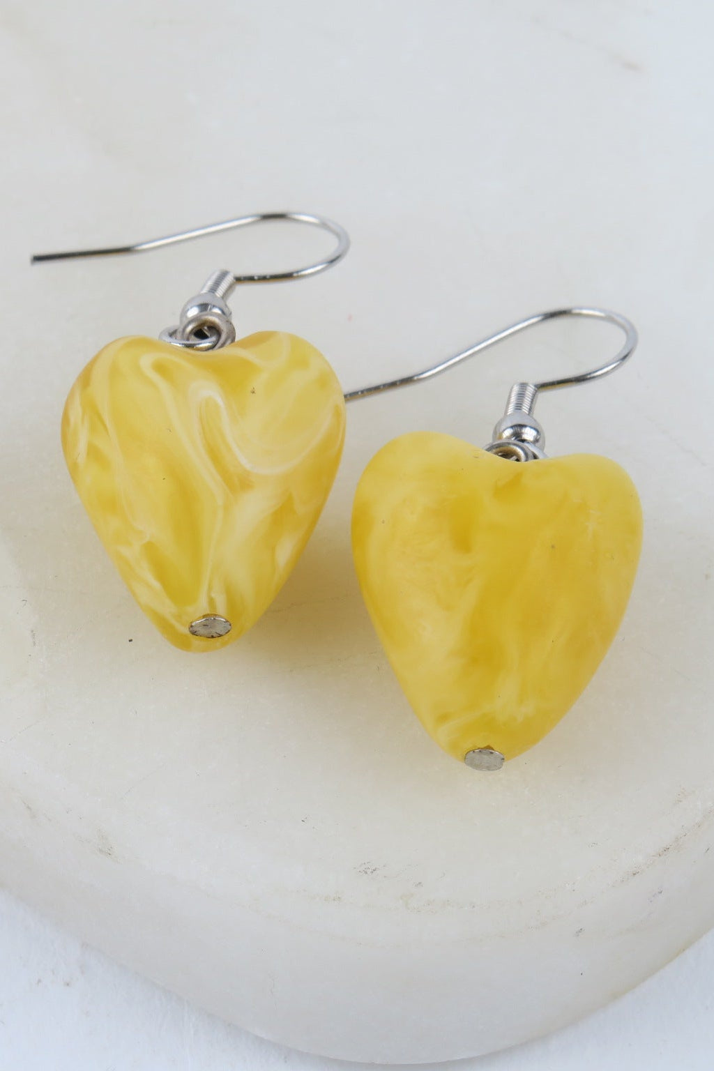 Heart-shaped yellow earrings on a white background