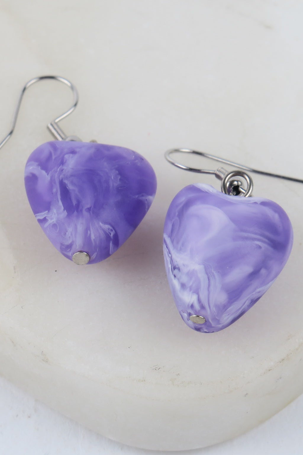 Purple marbled earrings on a white background