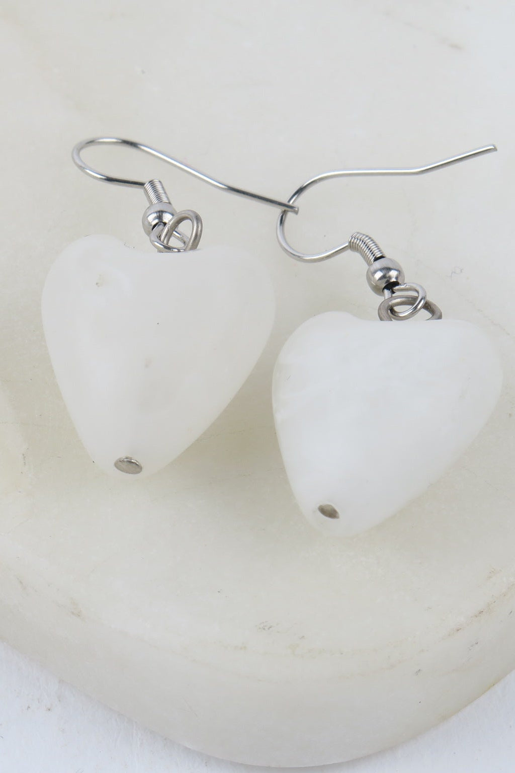 Heart-shaped white earrings on a white background