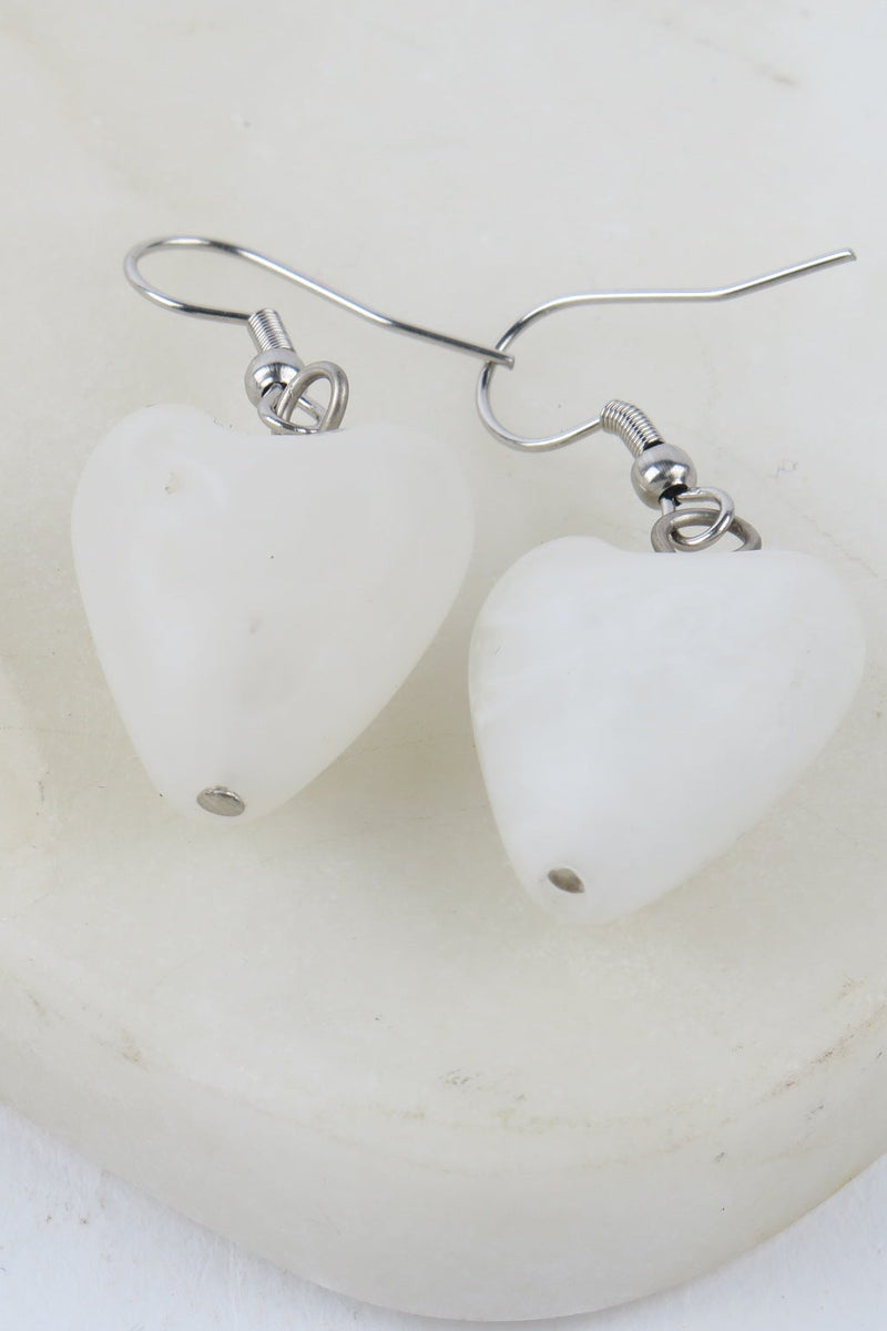 Heart-shaped white earrings on a white background