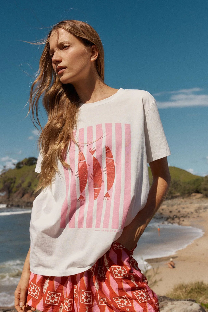 Woman wearing a white t-shirt with a red graphic design on a beach