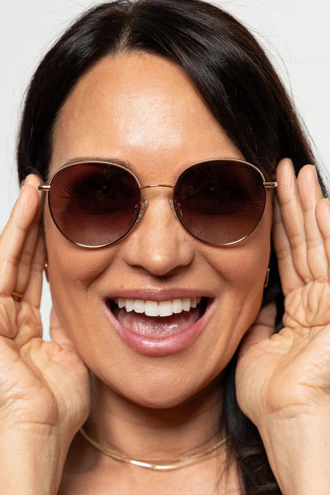 Woman wearing round sunglasses with a neutral background