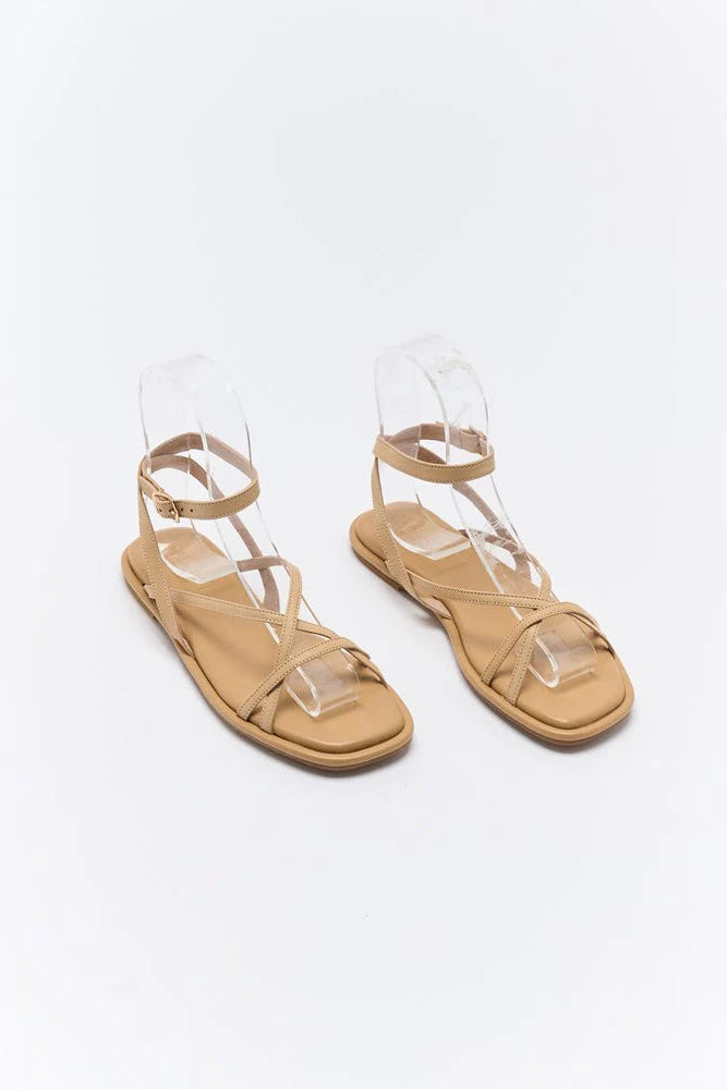 Pair of beige sandals with clear straps on a white background