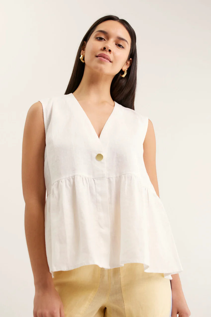 Woman wearing a white sleeveless top with a plain background