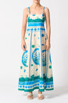 Woman wearing a long dress with blue and green patterns on a white background