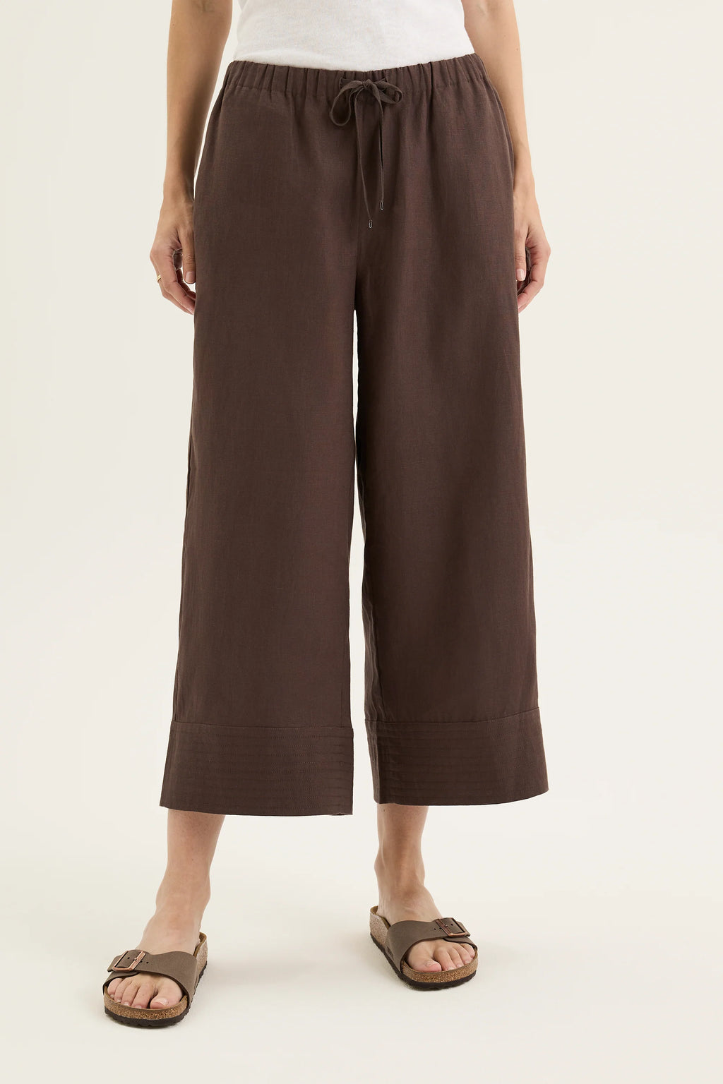 Person wearing brown wide-leg pants on a white background