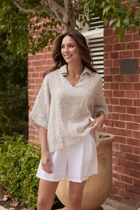 Woman in a light outfit standing in front of a brick building